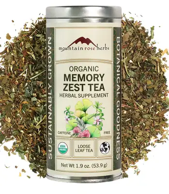 The Mountain Rose Herbs Organic Memory Zest Tea round metal tin with its cream label and green side bands, with loose herb blend spilled around it